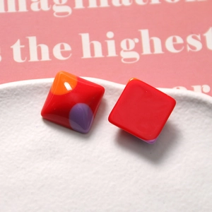 Macro detail of geometric resin charms with colorful red and orange glazed mosaic finish