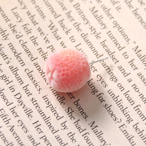 Detailed macro shot of a pink-orange flocked spherical stud earring with subtle glitter