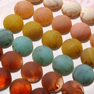 Flat lay of half-round resin beads with ink-wash marble patterns and matte finish