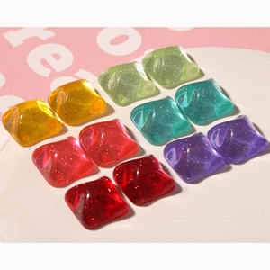 Macro shot of 12 square glittery resin charms in vibrant candy colors for DIY jewelry