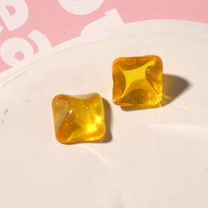 Macro shot of yellow translucent resin square charms with glitter for DIY jewelry making