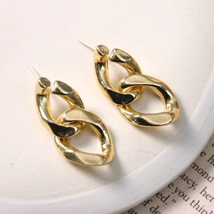 Polished gold interlocking chain link stud earrings in a minimalist jewelry display