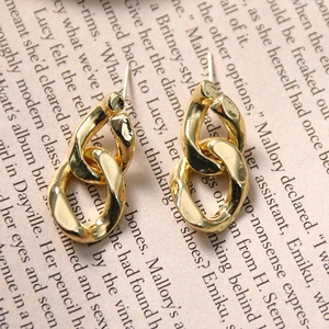 Detailed view of interlocking gold metal chain link earrings on a vintage paper background