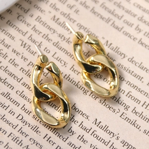 Vintage golden chunky chain earrings with textured metal finish on an aesthetic book page