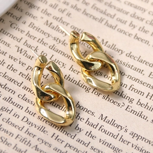Macro detail of retro golden chain link earrings on vintage book background