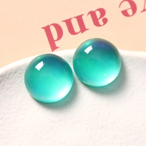 Macro-opname van twee halfronde mintgroene hars cabochons op een wit getextureerd dienblad
