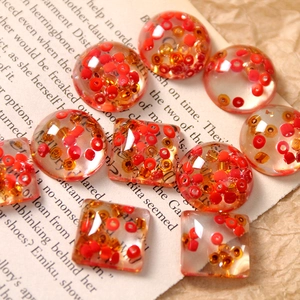 Macro shot of resin cabochons with red glass beads for DIY earring and hair clip jewelry