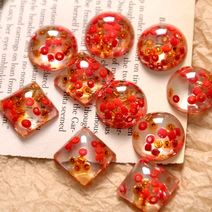 Macro shot of resin beads with red and gold micro-seeds for DIY jewelry making