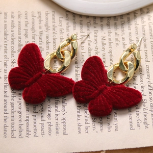 Close-up of vintage wine red velvet butterfly earrings with gold chain on retro book page