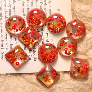 Close-up of handmade resin beads with red seed beads on vintage paper background