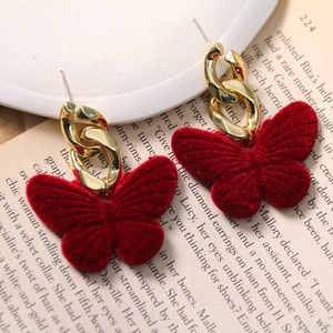 Detail of red flocked butterfly earring with gold metal chain on vintage paper