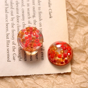 Detailed macro view of clear resin semi-sphere beads with red and orange seed beads inside