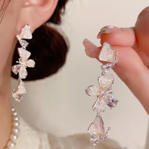 Detalle de pendientes de borla con mariposa de cristal degradado y aguja de plata