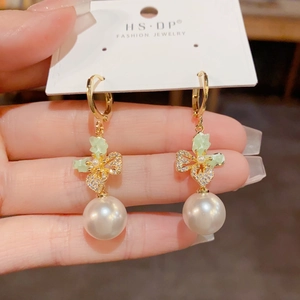 Detail of elegant butterfly zircon earrings with hanging pearl and gold leaf accents