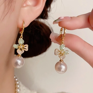Detail of zircon butterfly earrings featuring green leaves and soft purple pearls
