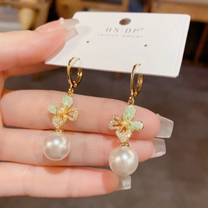 Detail of gold butterfly pearl earrings with sparkling crystals and elegant hoop design