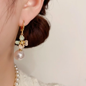 Elegant zircon butterfly pearl earrings with pink-purple luster on a model