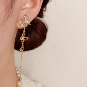 Detail of long butterfly tassel earrings with sparkling white crystals and gold chains