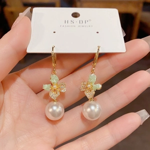 Elegant gold earrings with pearl drop and green crystal butterfly pendant in a chic hand-held view