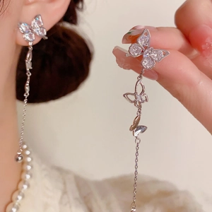 Detail of silver butterfly tassel earrings with sparkling zircons on elegant hand display