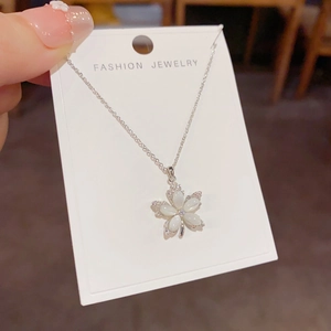 Detailed shot of five-petal shell flower pendant necklace with diamonds on display card