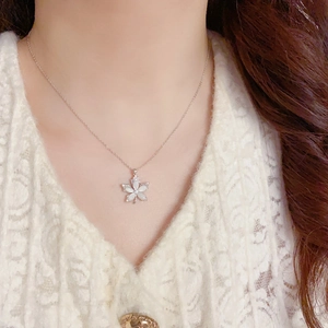 Elegant maple leaf pendant necklace with white shell beads on a silver-tone chain