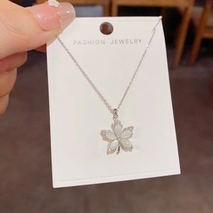 Close-up of a silver flower necklace with white opal petals and zircon accents