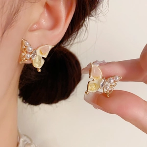 Dettagli di orecchini a farfalla con perle, strass e smalto con sfumatura