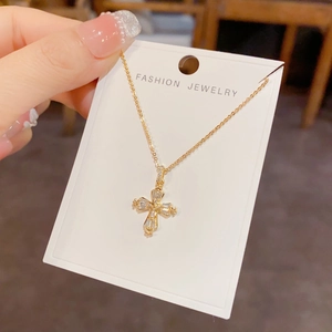 Gros plan du collier pendentif croix dorée avec zircons brillants sur carte de vente