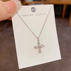 Détail macro d'un pendentif croix serti de zircons sur une chaîne de ton argent