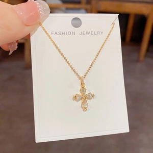 Élégant collier pendentif croix dorée serti de strass sur carte de bijouterie