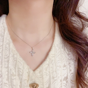 Gros plan du collier pendentif croix en argent avec oxydes de zirconium sur cou femme