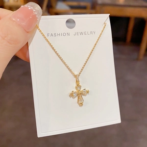 Gros plan d'un collier pendentif croix dorée avec strass scintillants sur carte de support