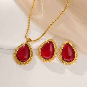 Detalle de conjunto de joyas bañadas en oro 18k con piedras rojas de gota y bordes dorados