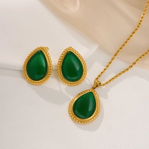 Vista detallada del collar con colgante de esmeralda y pendientes de gota dorados