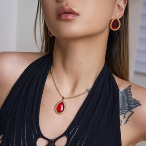 Primer plano de conjunto de collar y pendientes de gota roja con marco dorado en modelo