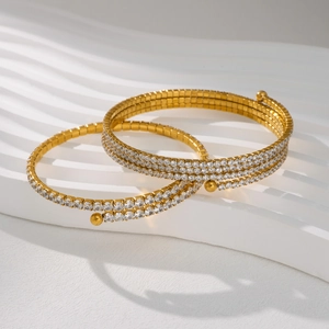 Detailed close-up of two gold 18k plated titanium bangles with shimmering micro-pave crystals