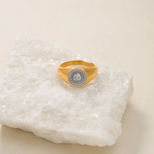 Close-up of two-tone signet ring with golden band and silver sun face relief design