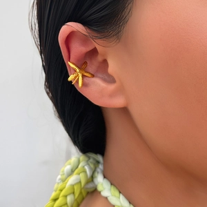 Macro detail of a 18K gold plated starfish ear cuff worn on a model's ear