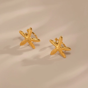 Macro view of gold starfish earrings with detailed grainy texture and metallic finish