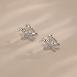 Macro view of silver starfish ear cuffs showing detailed metallic texture and finish