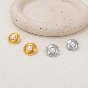 Macro view of vintage style 18k gold plated pearl shield earrings on stone tray