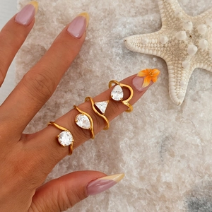 18k gold plated geometric ring set with crystal zircon stones on a beach sand background