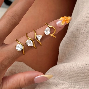 Close-up of four gold 18k plated rings with geometric cubic zirconia on a model finger
