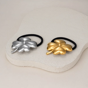 Detail showing 18k gold and silver clover hair ties on a natural stone background