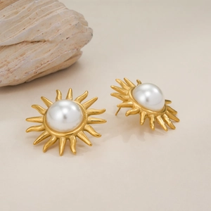 Detail of 18k gold plated sunburst earrings with a central pearl and seashell accent