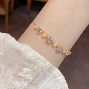 Elegant gold bracelet with opal stones and zircons worn on a white lace sleeve
