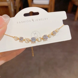 Detail of adjustable gold bracelet featuring round cat-eye stones and cubic zirconia