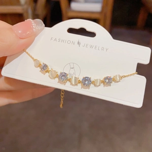 Macro view of gold bracelet with alternating white cat eye stones and sparkling zircons