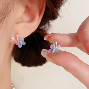 Detail of a color-gradient butterfly stud earring with pearl and crystal on ear